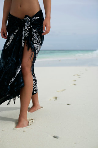 Young girl walking along the beach, footprints on the sand