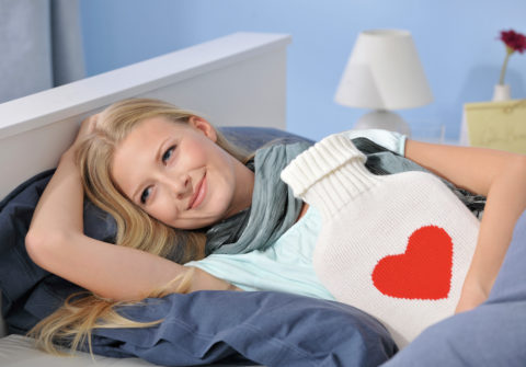 Woman lying in bed with hot-water bottle