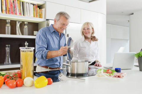 Senior couple preparing healthy pasta meal in kitchen