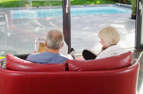 Senior couple on couch reading newspaper