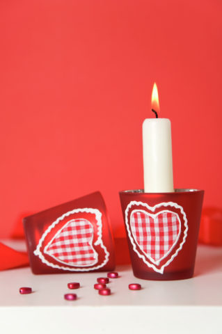 Burning candle with heart-shaped candle holders