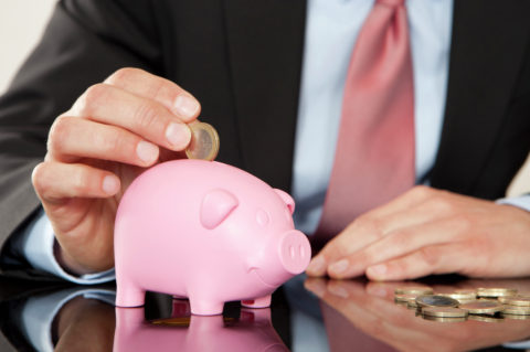 Businessman putting coin into piggy bank