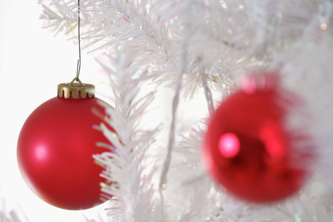 Two red Christmas tree balls on a white Christmas tree