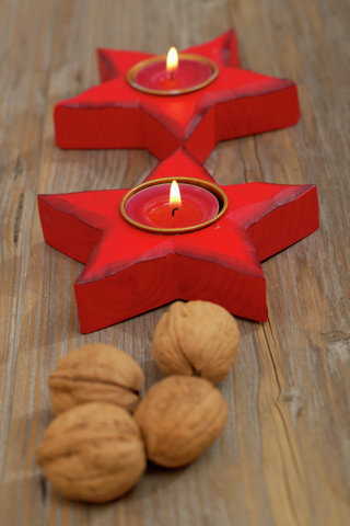 Star shaped candleholder with burning tea candles and walnuts