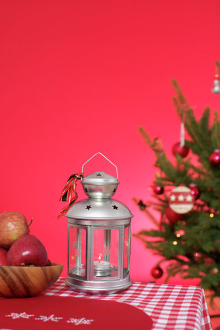 Christmassy decorated table with lantern, Christmas tree in background