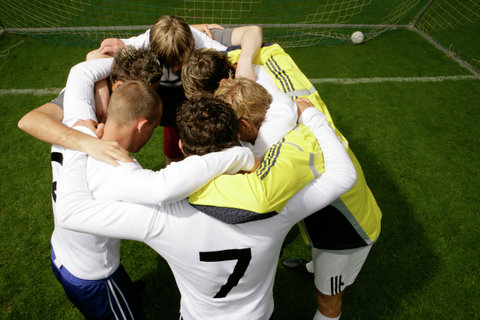 Footballers of one team and their goalkeeper hugging each other before a game