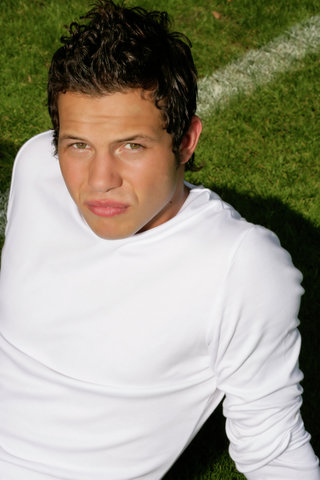 Young man with brown hair sitting on a pitch, close-up