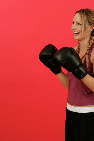 A laughing woman wearing boxing gloves