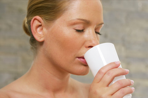 Young woman with closed eyes drinking of a glass
