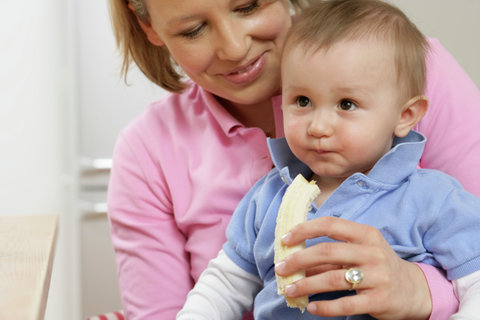 Mother feeding son witch a banana