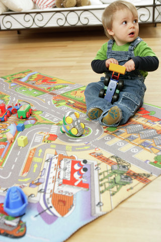 Baby boy with toy sitting on a play carpet