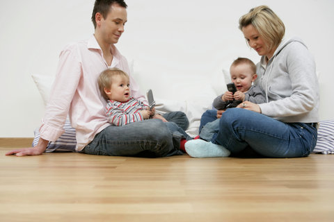 Mother and father sitting vis-à-vis, sons playing with mobile phones