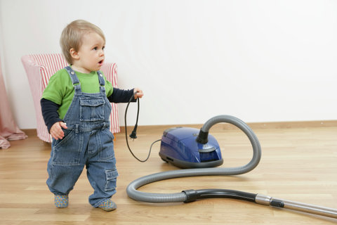 Baby boy holding a cable of a vacuum cleaner