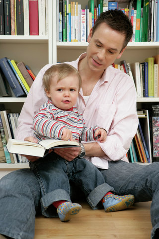 Father and son sitting in front of a shelf, baby boy looking angry