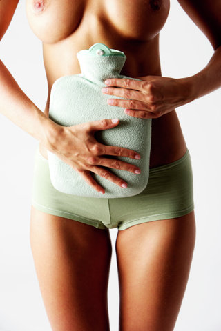 Skinny young woman holding a hot-water bottle against her belly (part of)