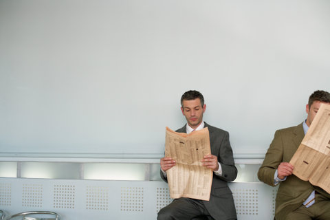 Two businessmen reading newspaper