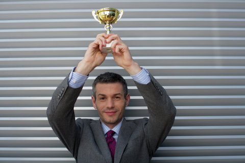 Businessman holding a trophy above head