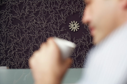 Businessman holding a cup of coffee, a wall clock in the background