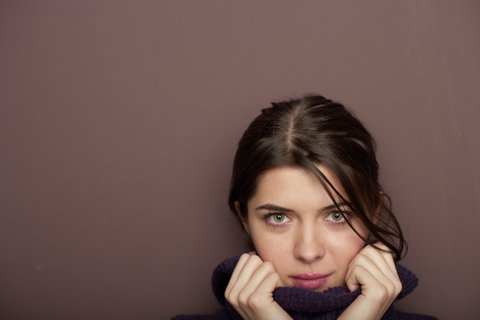 Young brunette woman holding the brim of a turtleneck, close-up, portrait