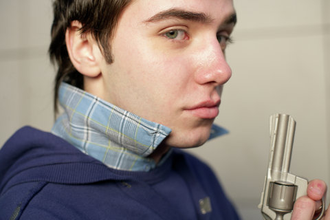 Young man with a gun looking at camera