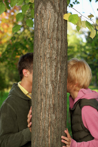 Teenage couple kissing behind a tree, selective focus