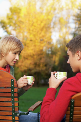 Teenage couple is having tea in a park, selective focus