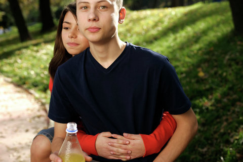 Teenage couple embracing, boy looking at camera