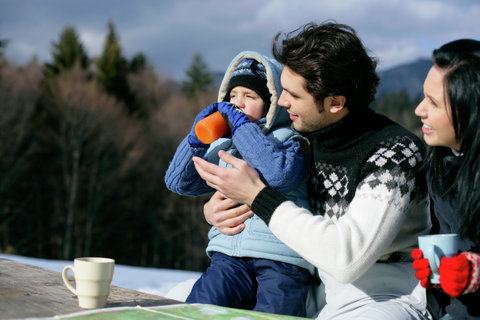 Couple drinking coffee, father helping son to drink juice