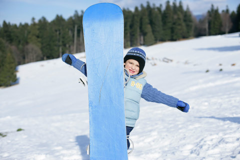 Boy standing behind a snowboard
