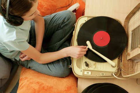 Girl listening to music of a record player by earphones