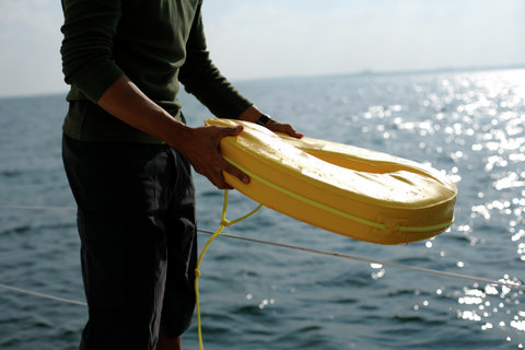 Man on a sailboat holding a life ring in his hands