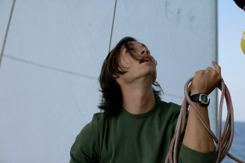 Man coiling ropes and looking up