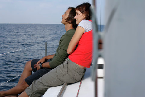 Couple sitting at border of a sailboat, looking over the sea