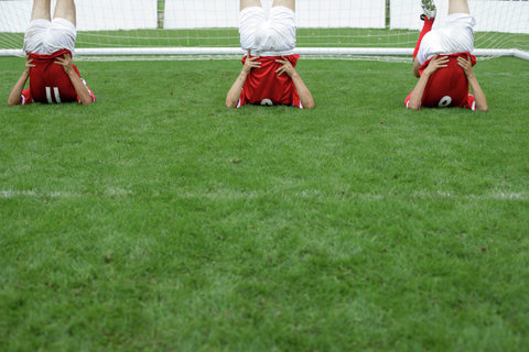 Soccer players doing stretching exercise in front of the goal