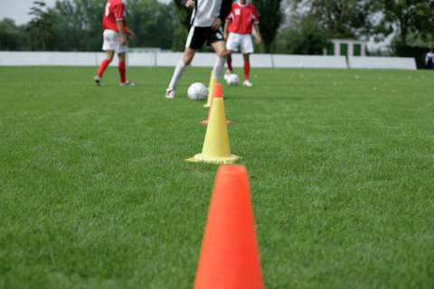 Soccer player running slalom with a football around marks