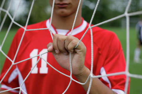 Soccer player clutching at goal net
