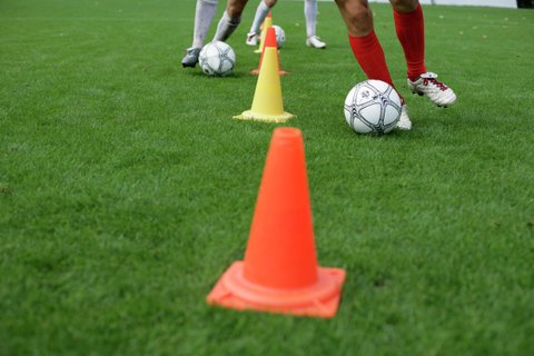 Soccer player running slalom with football around marks