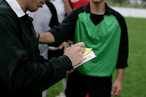 Referee noting a yellow card placing