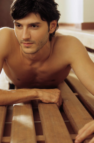 Darkhaired Man lying procumbently on a wooden Bench - Look - Allurement