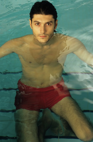 Darkhaired Man kneeling on the Stairs of a Swimming Pool - Baths - Leisure Time