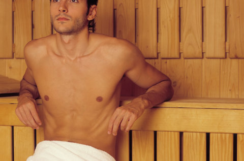 Darkhaired Man resting his Arms on a wooden Bench - Heat - Sauna - Wellness