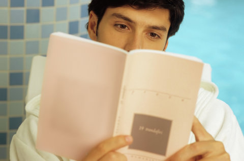 Darkhaired Man in a Bath Robe reading a Book - Wellness - Leisure Time - Print Media