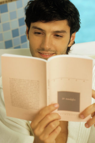 Darkhaired Man in a Bath Robe reading a Book - Wellness - Leisure Time - Print Media