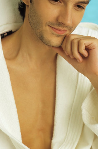 Darkhaired Man in a Bathrobe sits on a Canvas Chair laughing - Baths - Leisure Time - Wellness